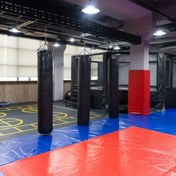 An octagonal kickboxing cage with boxing bags in the sports complex