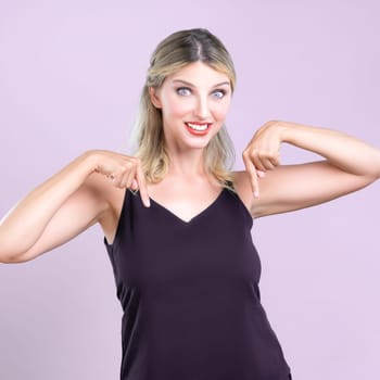 Alluring portrait of beautiful woman with perfect makeup and flawless clean skin pointing finger down in pink isolated background. Promotion indicated by hand gesture concept for advertisement.