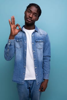 vertical portrait of handsome young stylish african man with curls in denim clothes.