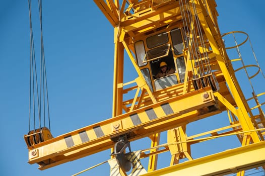 A worker in the cabin controls a construction crane