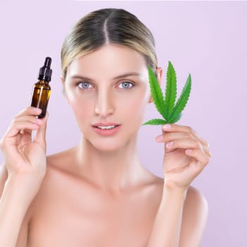 Alluring portrait of beautiful woman in pink isolated background holding green leaf with marijuan extracted bottle for skincare treatment product. Cannabis CBD oil for cosmetology and beauty concept.