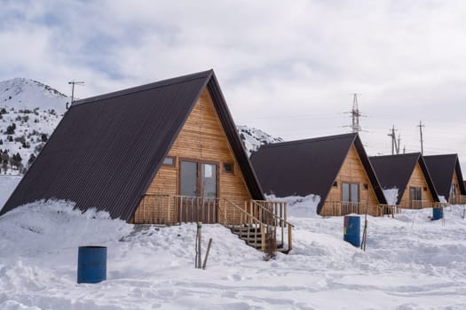 The wooden cottages surrounded by snow. A recreation area in the mountains