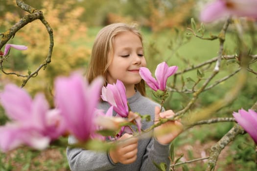 A little girl smelling pink magnolia