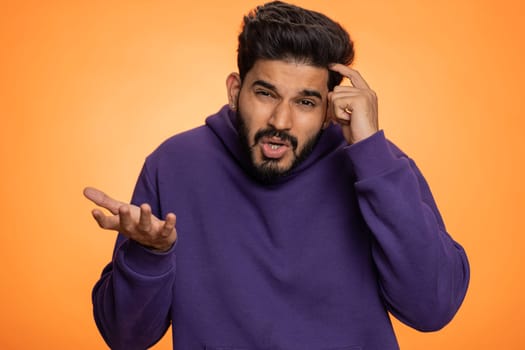 No idea, I dont know answer. Puzzled clueless uncertain indian handsome man raising hands in helpless gesture, embarrassed confused by difficult question. Confused one guy on orange studio background