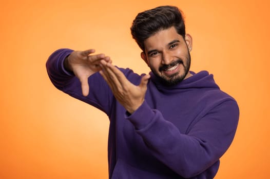 Indian man showing wasting, throwing money around, more tips, big profit, winning lottery jackpot, successful shopping payment purchase, cashback, victory celebrate. Hindu guy on orange background