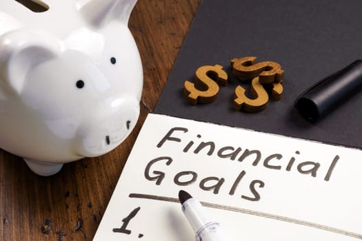 A Piggy bank and open notepad with inscription financial goals and list.