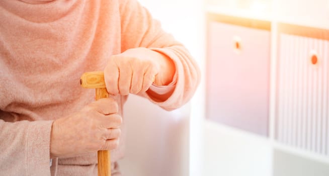 hands of old woman holding cane in room