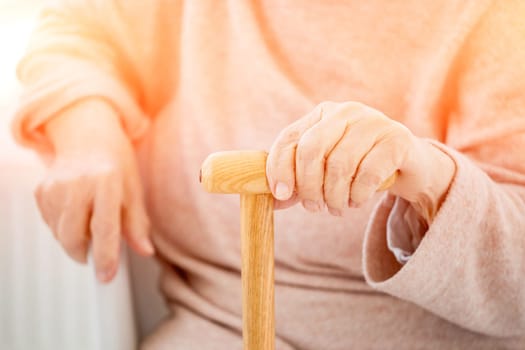 hand of aged woman with cane on light background