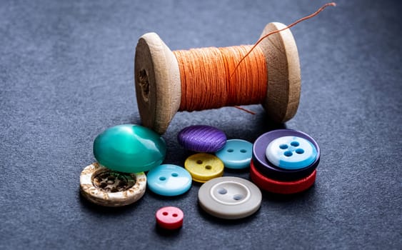 Colorful sewing buttons and orange thread spool macro