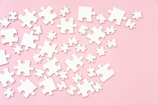 White jigsaw puzzle pieces on pink, top view