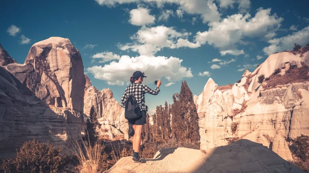 Tourist with camera standing between rocky mountains of Cappadocia, Turkey