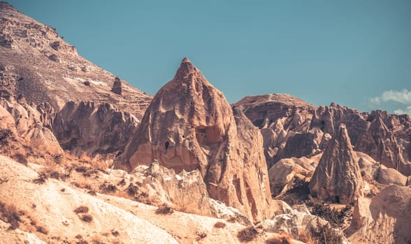 Landscape with houses in Cappadocia mountains under blue sky, Turkey