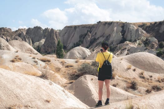 Woman standing backwards while photographing landscape in Cappadocia, Turkey