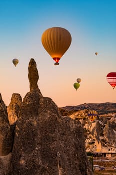 Lots of hot air balloons floating in sunset sky