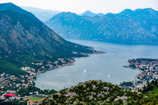 Panorama of Kotor bay and city in Montenegro with aerial view from mountain. Scenic landscape with ancient architectire with red roofs and Adriatic sea