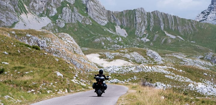 Motocycle biker ride in the mountains on serpentin road. Moto driver and amazing nature landscape