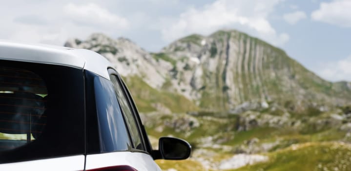 White car with the mountains on background. Vehicle in beautiful landscape of national park in sunny day