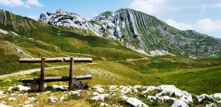 Wooden bench in mountains of Montenegro in National park Durmitor with scenic nature view. Amazing balkan landscape in sunny summer day