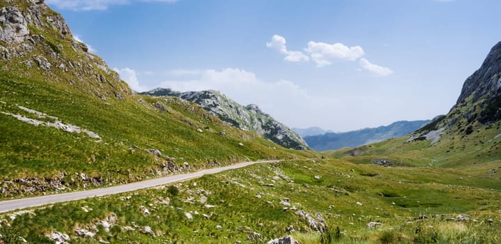 Scenic road with mountains view in National park Durmitor in Montenegro. Amazing balkan nature in sunny summer day with blue sky