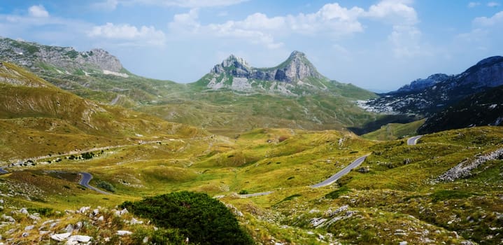 Amazing mountains view with serpentine road in National park Durmitor in Montenegro. Scenic panoramic nature view in summer day with blue sky