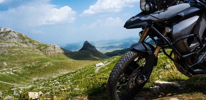 Motocycle standing in the mountain pick in National park Durmitor in Montenegro with amazing nature landscape, closeup view on vehicle