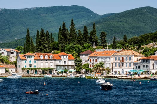 Scenic Mediterranean city in Montenegro with mountains, view from Adriatic sea. Beautiful architecture with orange roofs