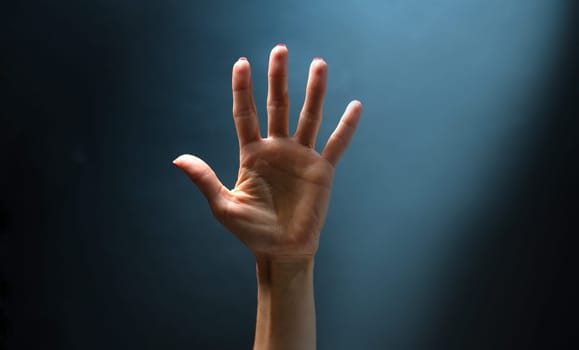 Female hands with fingers up on blue background. Concept of gesture communication with no words