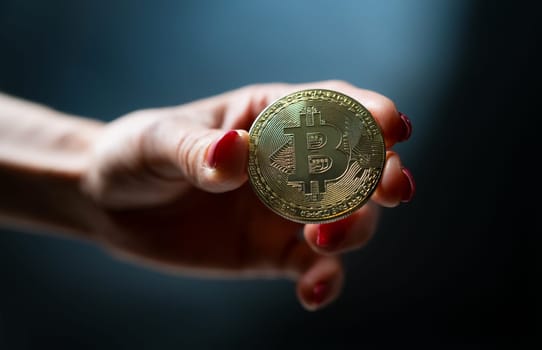 Female hand holding golden bitcoin virtual currency coin. Btc digital cyberspace money of future and symbol of mining and blockchain technology