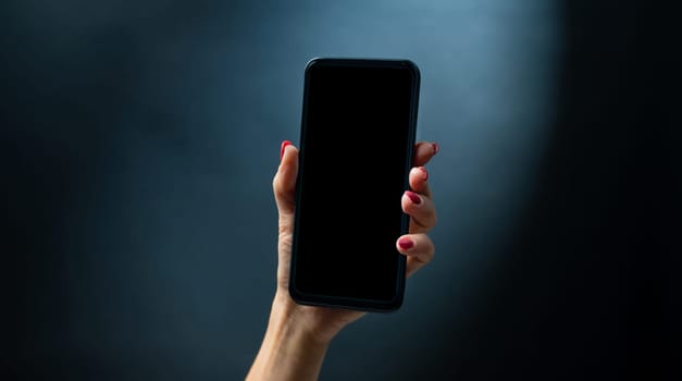 Hand holding smartphone with black copy space on screen. Female person with modern mobile cell phone and digital technology