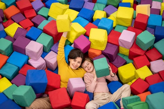 Pretty girl on trampoline holding colorful cube and smiling. Young woman happy during entertaiments at playground park