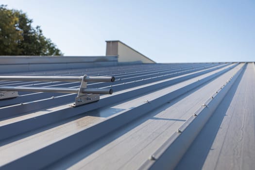 Systemic protection on the roof against sliding snow. Steep roof covered with trapezoidal sheets coated with graphite-colored paint.