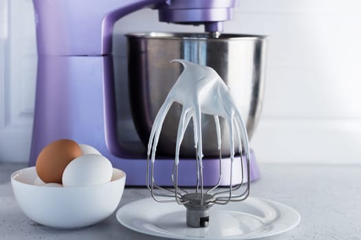 Modern mixer on the kitchen table with eggs and whipped meringue.