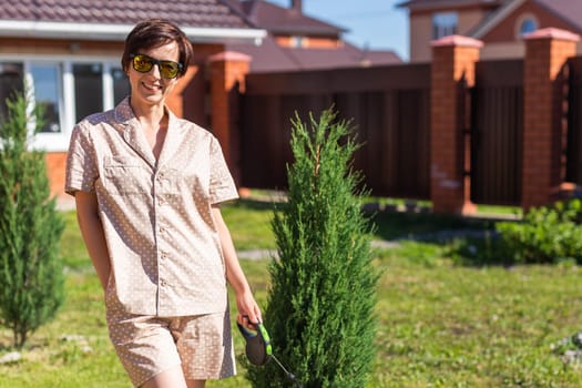 Young woman wearing pajama with her dog on backyard. Concept of animals and friendship or pet owner and love