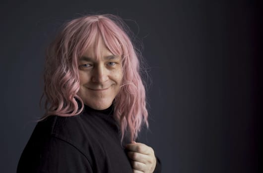 Portrait of a positive man in a pink wig. Close-up