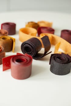 Fruit marshmallows rolled up lies on the table. Close-up.