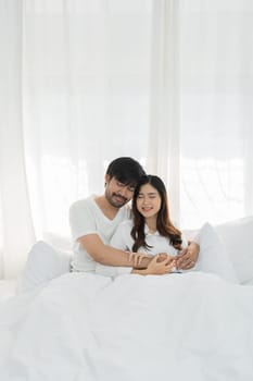 Asian Romantic couple in bed enjoying sensual foreplay Happy sensual young couple lying in bed together. Beautiful loving couple kissing in bed