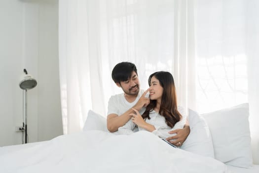 Asian Romantic couple in bed enjoying sensual foreplay Happy sensual young couple lying in bed together. Beautiful loving couple kissing in bed