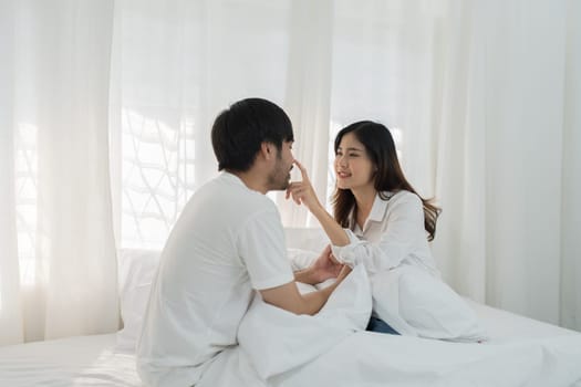 Asian Romantic couple in bed enjoying sensual foreplay Happy sensual young couple lying in bed together. Beautiful loving couple kissing in bed