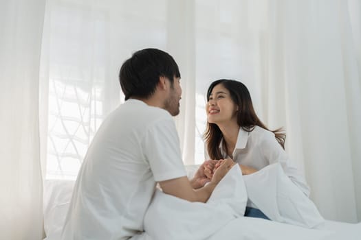 Asian Romantic couple in bed enjoying sensual foreplay Happy sensual young couple lying in bed together. Beautiful loving couple kissing in bed