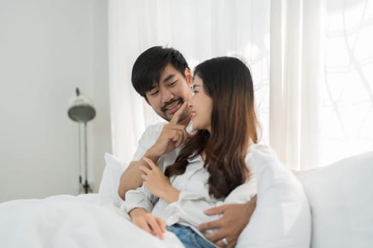 Asian Romantic couple in bed enjoying sensual foreplay Happy sensual young couple lying in bed together. Beautiful loving couple kissing in bed