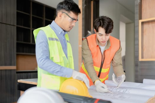 multi ethnic engineer brainstorming and measuring for cost estimating on paperworks and floor plan drawings about design architectural and engineering for houses and buildings.