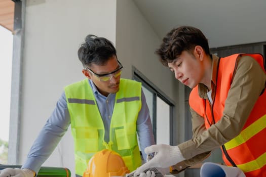 multi ethnic engineer brainstorming and measuring for cost estimating on paperworks and floor plan drawings about design architectural and engineering for houses and buildings.