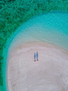 couple of men and women on the beach of Ko Lipe Island Thailand. drone aerial view of a sandbank in the ocean on a sunny day