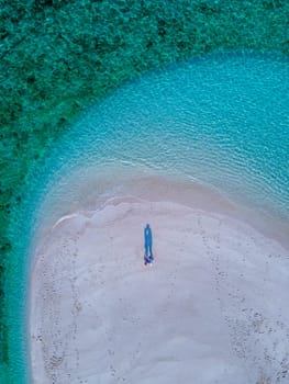 couple of men and women on the beach of Ko Lipe Island Thailand. drone aerial view of a sandbank in the ocean