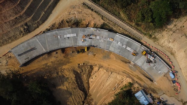Aerial view of development of new road construction or overpass under construction. Top view from a drone above road construction workers among the mountains.