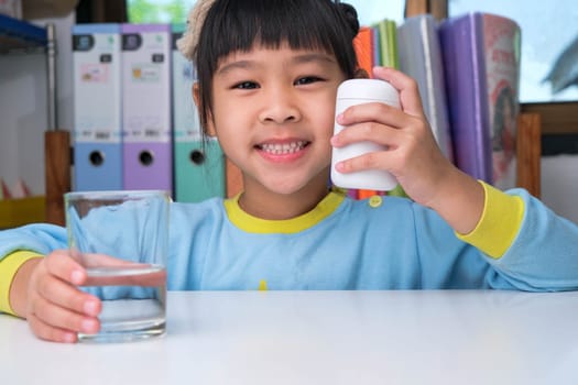 Cute little girl eating alpha omega 3 or Vitamin pill. Vitamin supplements for children for better immunity.