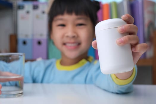 Cute little girl eating alpha omega 3 or Vitamin pill. Vitamin supplements for children for better immunity.