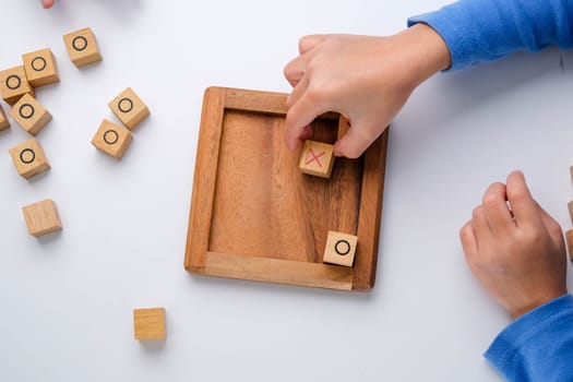 Little siblings playing wooden board game tic-tac-toe on table in living room. Family spending time together on weekend.