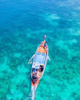 drone view at the beach of Koh Kradan island in Thailand, aerial view over Koh Kradan Island Trang with longtail boats in the turqouse colored ocean