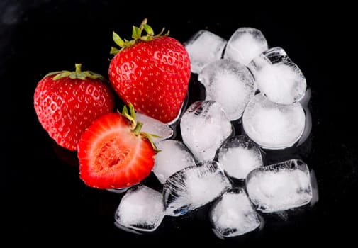 Ice cubes with strawberries on black background.